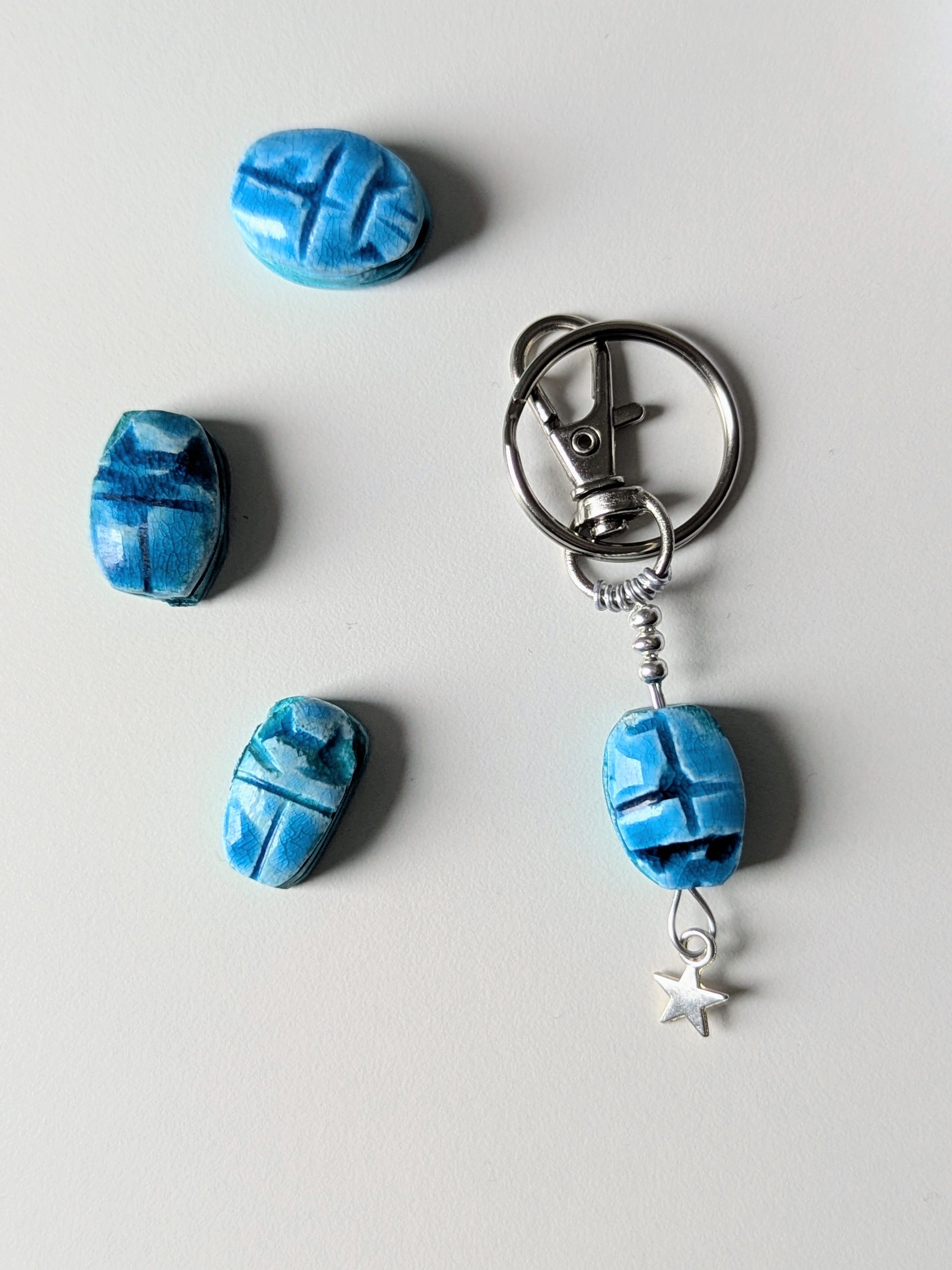 blue scarab on a silver wire keyring with sterling silver star with blue scarabs on a white background