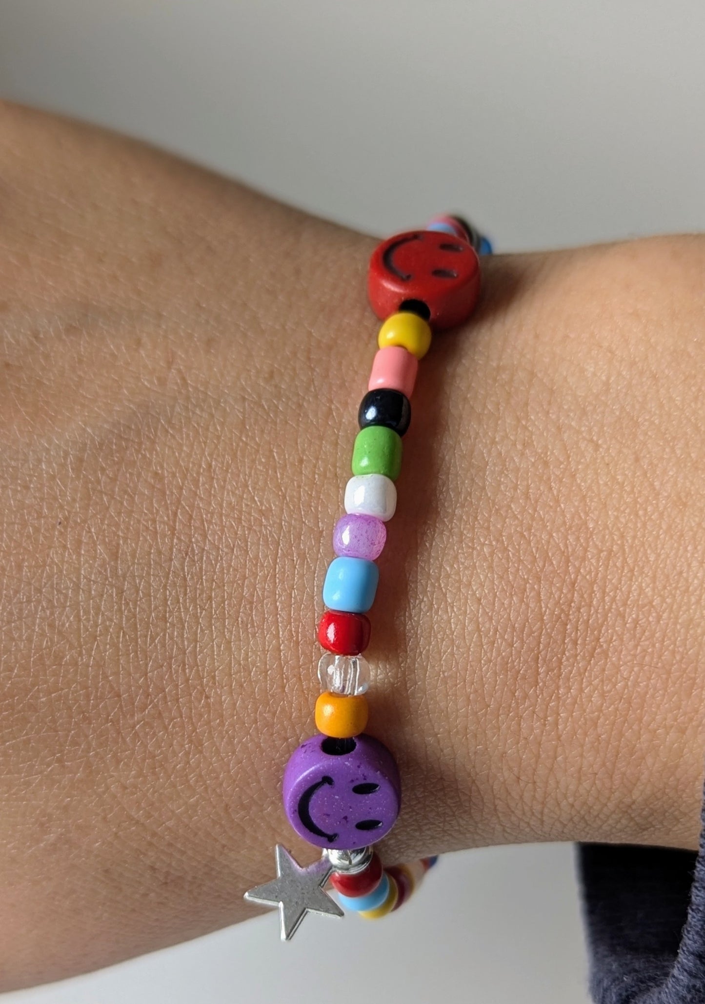 Colorful beaded bracelet with smiley face beads on a wrist against a neutral background